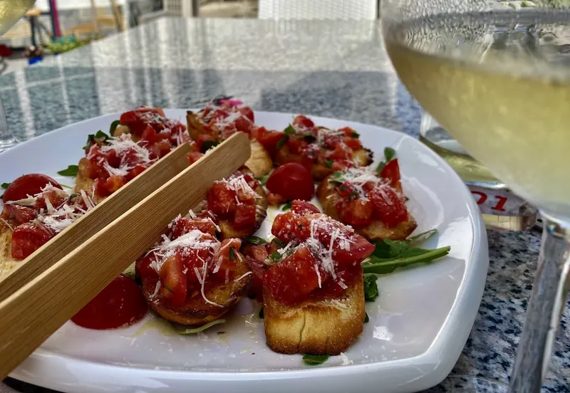 Bruschetta with tomato and grated cheese, served with tongs