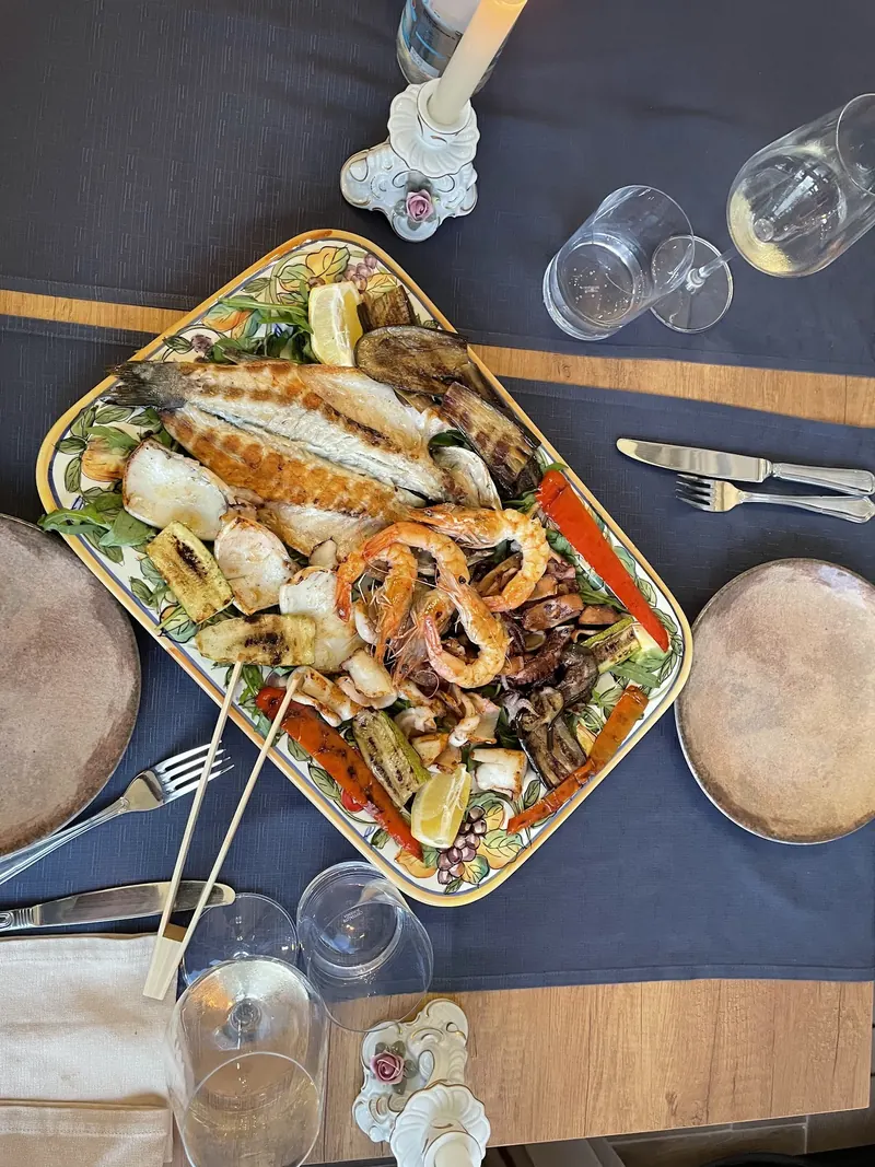 Grilled fish, prawns and vegetables on a ceramic platter, seen from above