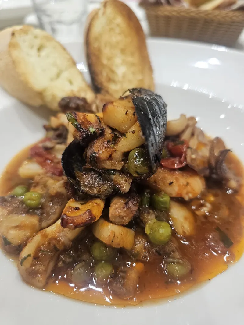 Octopus, mussels and squid stewed with peas and tomato