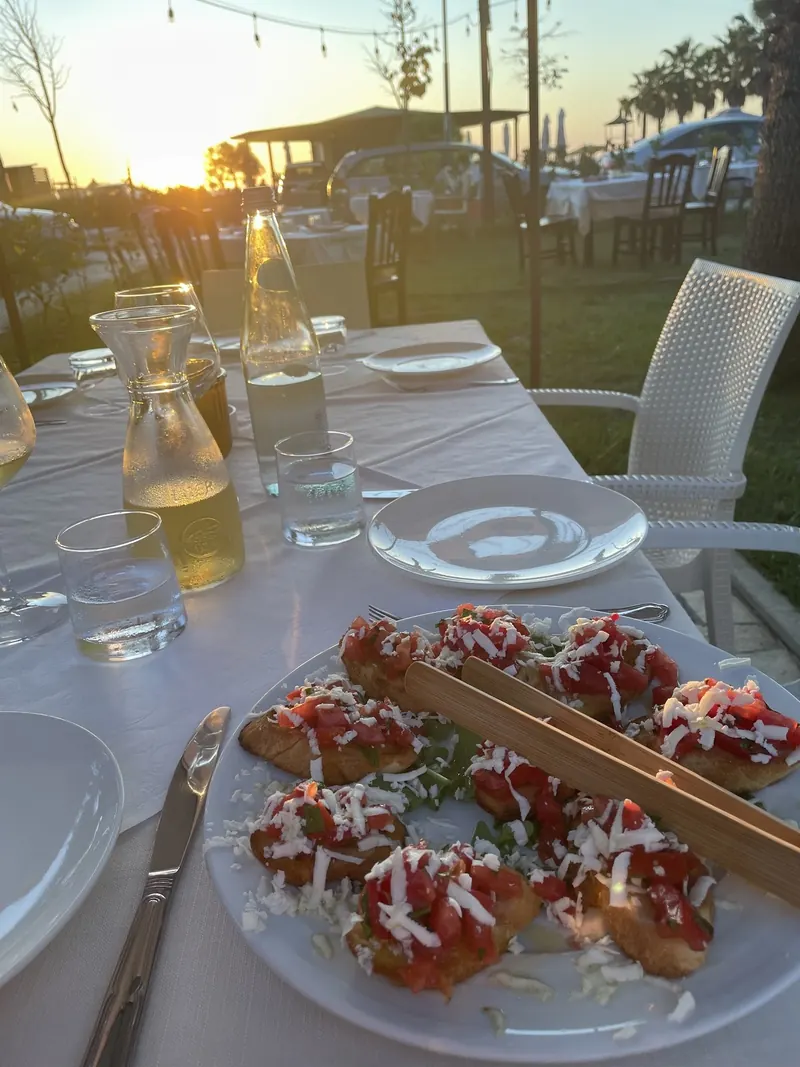A table on the Acqua Pazza garden terrace at sunset, with bruschetta, white wine and string lights