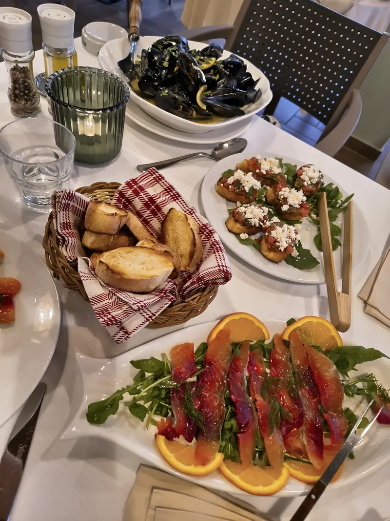 A shared table with mussels, bruschetta, bread and salmon with orange